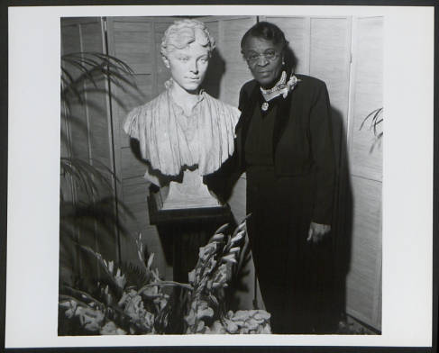 Portrait of Charlotte Hawkins Brown with a sculpture of Alice Freeman Palmer, taken in 1955. Alice Palmer was a friend of Charlotte Hawkins Brown and contributed to fundraising to build the Palmer Memorial Institute. This image is from the collection of the Charlotte Hawkins Brown state historic site.