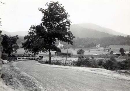 Photograph of a rural road and farm scene in North Carolina, ca. 1910-1910. Item H.19XX.317.4 from the N.C. Museum of History. Used courtesy of the N.C. Department of Natural and Cultural Resources.