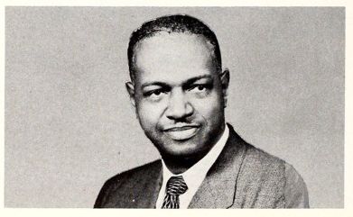 Black and white photo head and shoulders portrait of individual in a suit jacket and tie