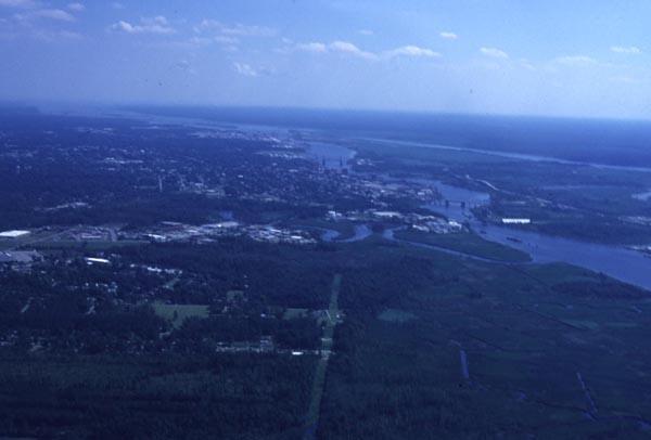 Aerial photo. Small plots of land and the Cape Fear River are visible. Mostly woodland. 