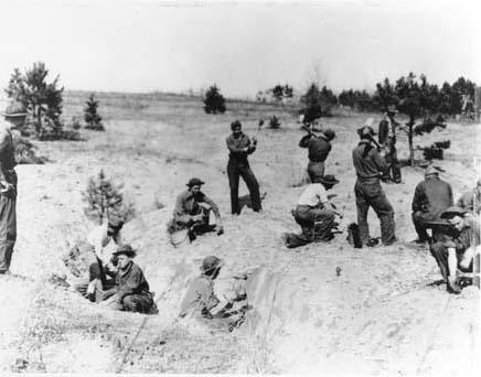 Young men plant trees in dusty soil.