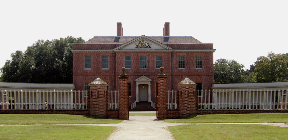 Tryon Palace. It is a two story, colonial-style, brick mansion. there are trees in the background, and an beige wings on the mansion.