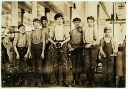Children in a mill. They are very young, likely eight to ten. They look tired. Sepia photo.