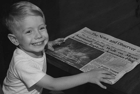 PHOTO OF DWAYNE CLARK, AGE 3 1/2 YEARS OLD, SON OF MR. & MRS. CHARLES CLARK, HOLDING A COPY OF THE "NEWS & OBSERVER," JULY 21, 1969, ANNOUNCING THE FIRST MOON LANDING