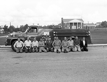 Fuquay-Varina Rural Fire Department firemen and equipment, fire truck in 1957. Photo taken on Academy Street in front of the Robert E. Prince Home, Fuquay-Varina, NC. From the Heulon Dean Photo Collection, PhC.133, North Carolina State Archives, call #:  PhC133_1957_142_A. 