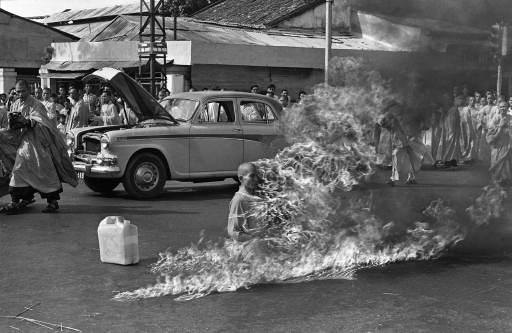 A monk lights himself on fire in protest while people watch.