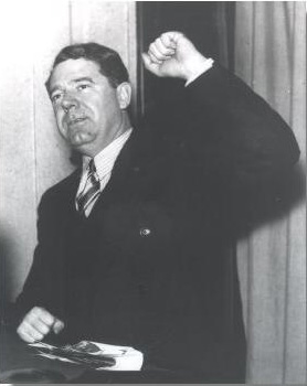Huey Long. He has his fist raised. He has short hair and a suit.