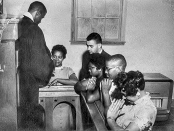 Durham pastor and civil rights leader Douglas E. Moore gives communion to five of the local youths who sat-in at the Royal Ice Cream Company shop in 1957. Courtesy Virginia Williams and the Civil Rights Heritage Project, Durham County Library.