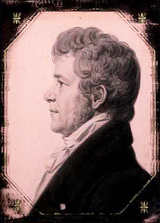 Thomas Blount. He is depicted wearing a coat and collared shirt. He is facing left and has thick curly hair. He is smiling. 